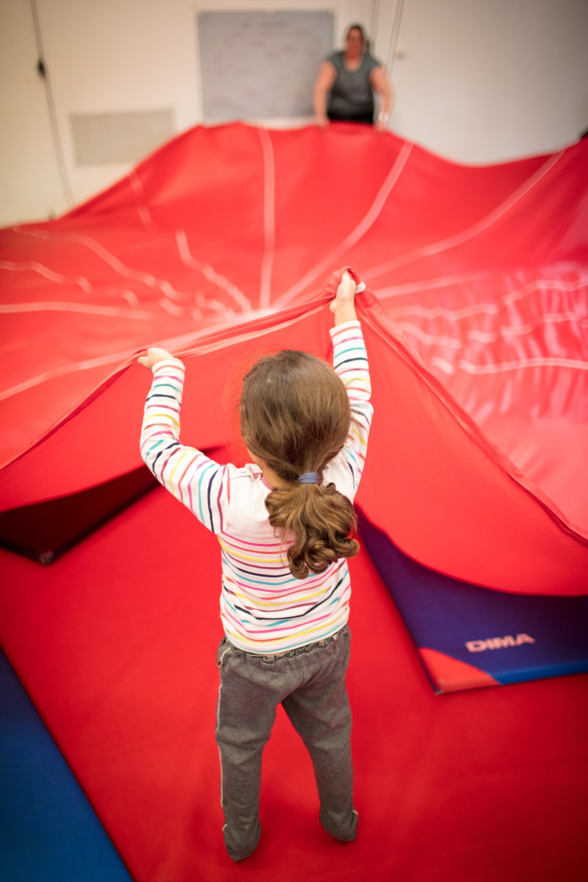 Enfant pratiquant le cirque avec un parachute rouge
